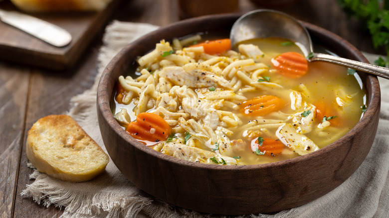 A spoon in a bowl of chicken noodle soup