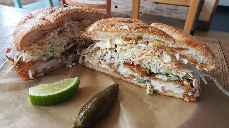 A fish torta with a pickled jalapeño and lime wedge