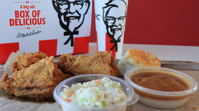 KFC's chicken, cole slaw, and a biscuit next to a bowl of gravy.