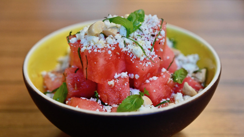 Watermelon feta salad with mint, blanched almonds, and a balsamic drizzle on wooden table