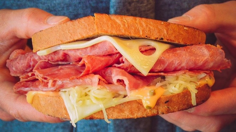 Hands hold up a Culver's Grilled Reuben Melt