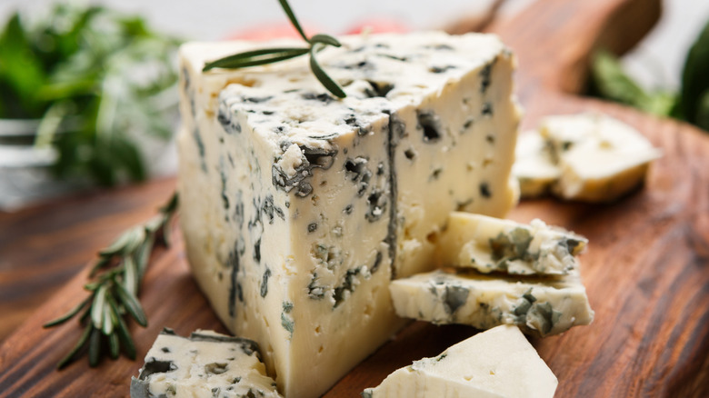 A wedge of bleu cheese on a wooden cutting board