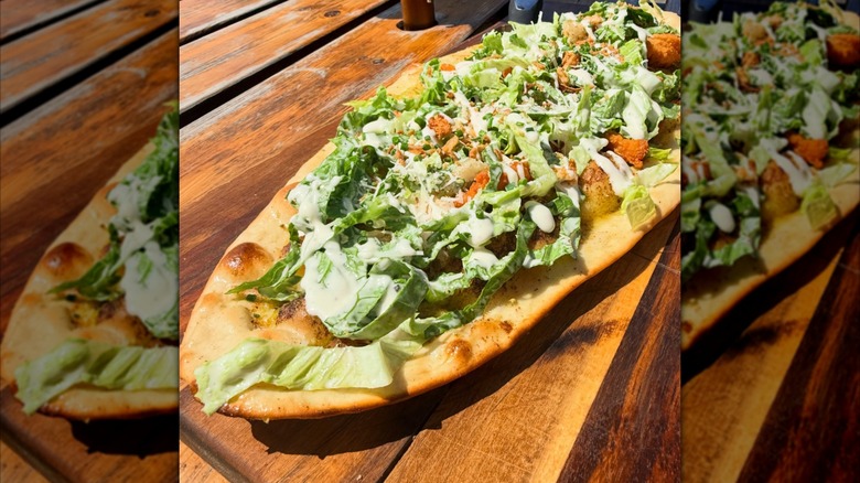 A Chicken Caesar salad pizza with no sauce or cheese, but a drizzle of herby olive oil instead.