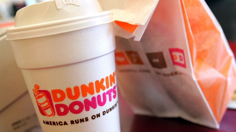 A cup of Dunkin' Donuts coffee and a takeout bag