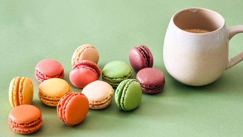 An assortment of macarons next to a cup of coffee