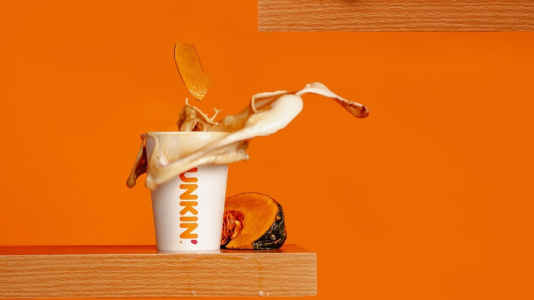 Dunkin to-go cup next to a wedge of pumpkin.