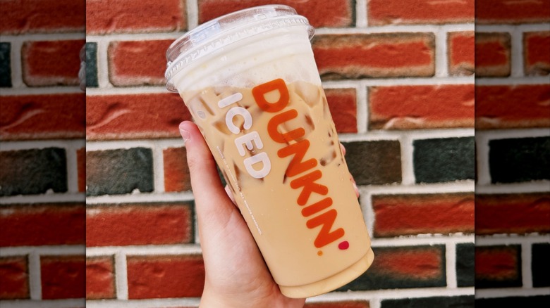 A small pumpkin spice latte from Dunkin', topped with foam and a blend of spices.