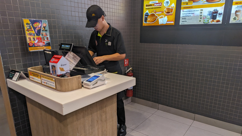 A McDonald's employee stands behind a cash register