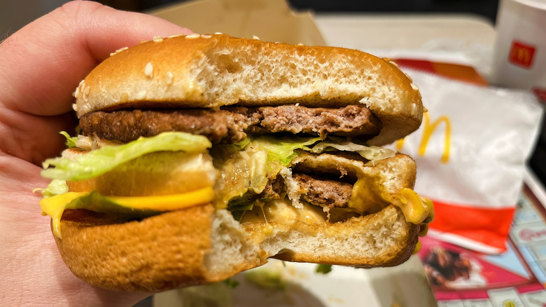 Someone holds a Big Mac with a bite taken out of it