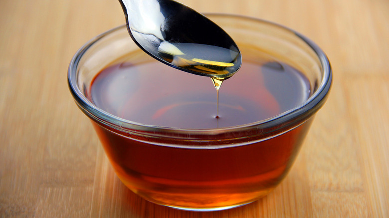 A spoonful and bowl of maple syrup.