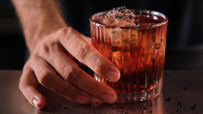 Hand holding a negroni with chocolate shavings on top