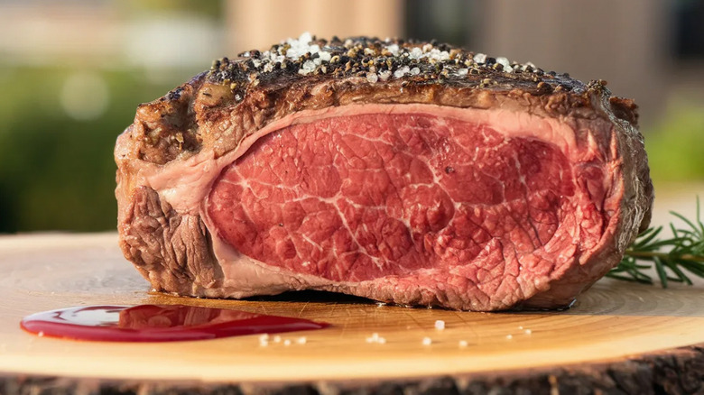 A slice of prime rib on a wooden board