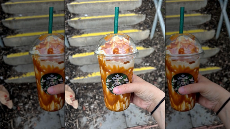 A hand holds a Starbucks drink lined with caramel sauce.