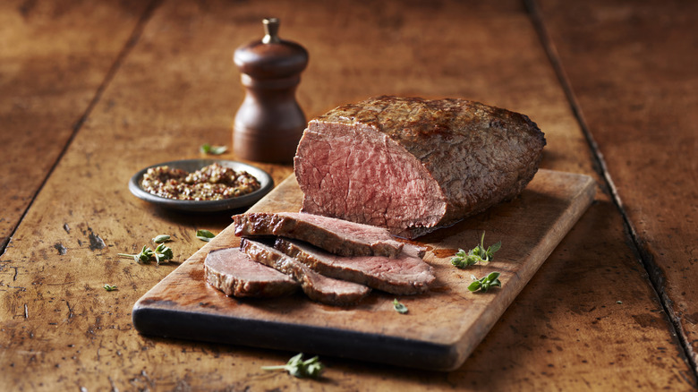 Steak cut into four slices with a dish of mustard and a pepper shaker