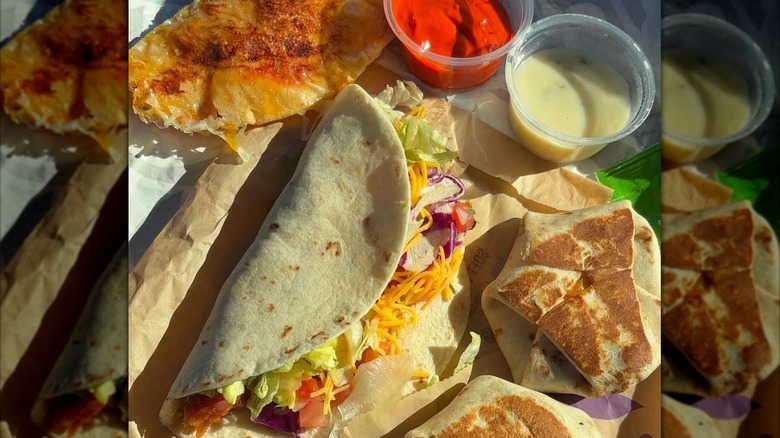Taco Bell tacos and mini crunchwraps next to pots of red and green enchilada sauce.