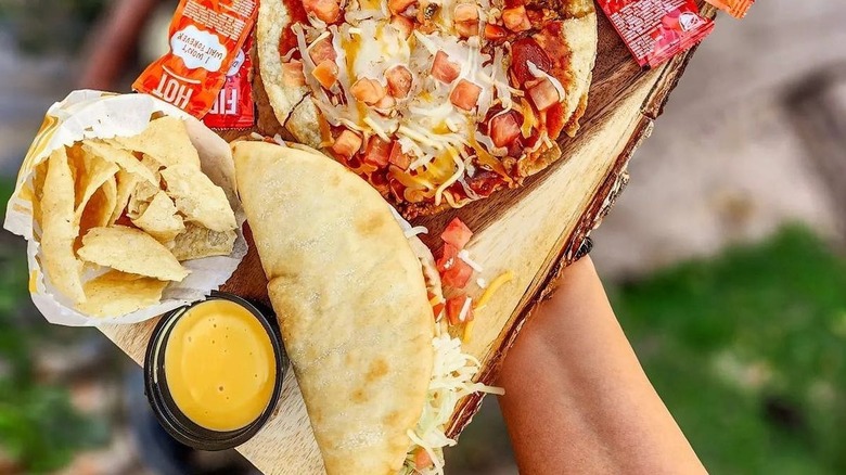 Nacho cheese next to tortilla chips, a chalupa, and a chicken Mexican pizza from Taco Bell.