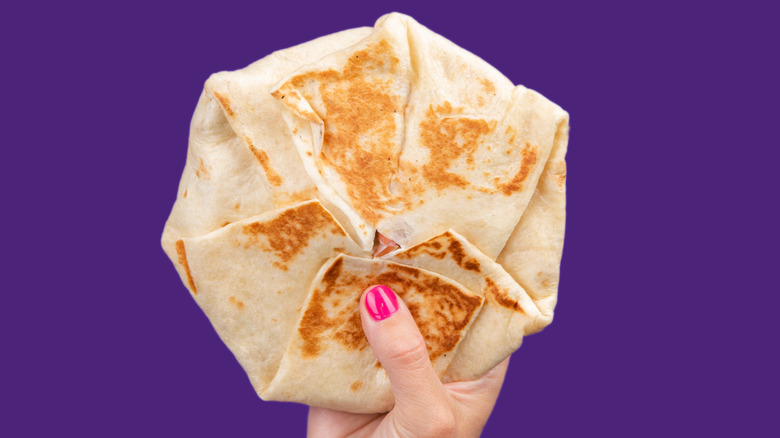 A hand holding a Crunchwrap.