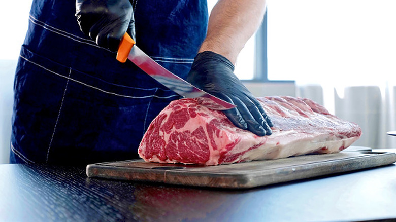 Someone carves into a slab of meat.