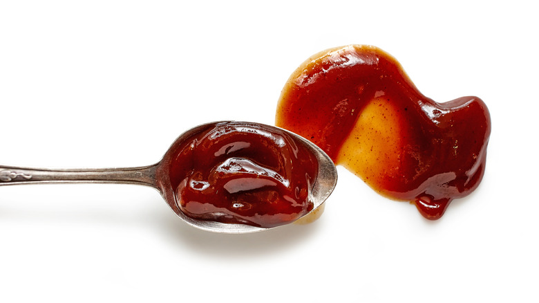 A spoonful of barbecue sauce smears the sauce on a white surface