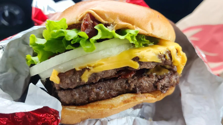 Closeup of a Baconator with vegetable toppings