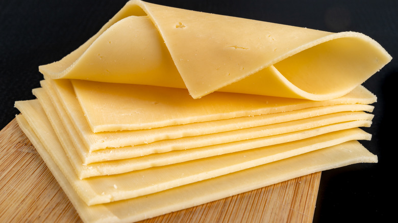 Slices of cheese on a wooden cutting board