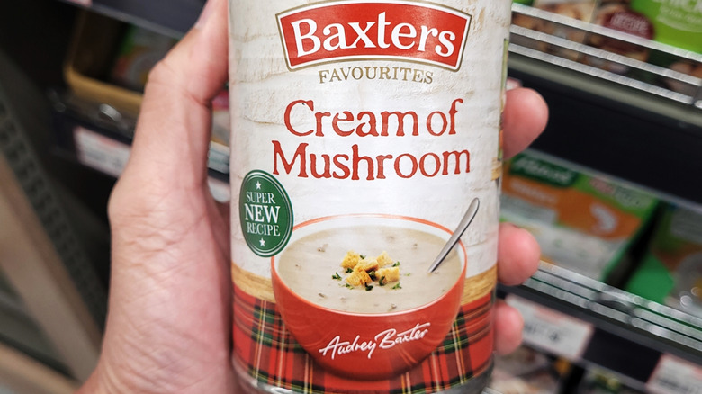 Hand holding a cream of mushroom soup can in store
