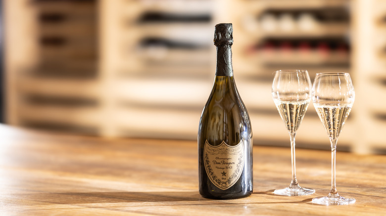 A bottle of Dom Perignon alongside two full Champagne glasses.