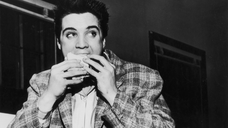 Elvis Presley eating a sandwich in black and white.