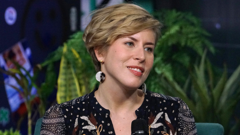 Erin Napier on a talk show smiling with plants in the background.