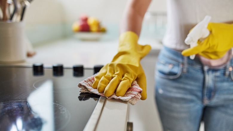 woman wiping down oven with yellow gloves on