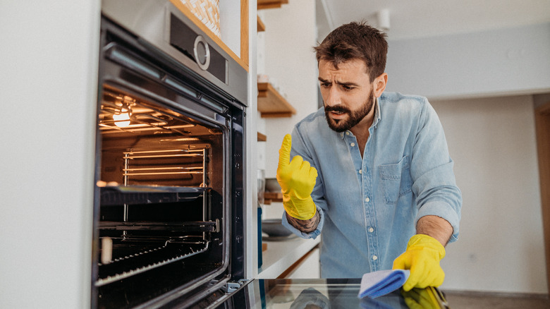 man cleaning inside of oven