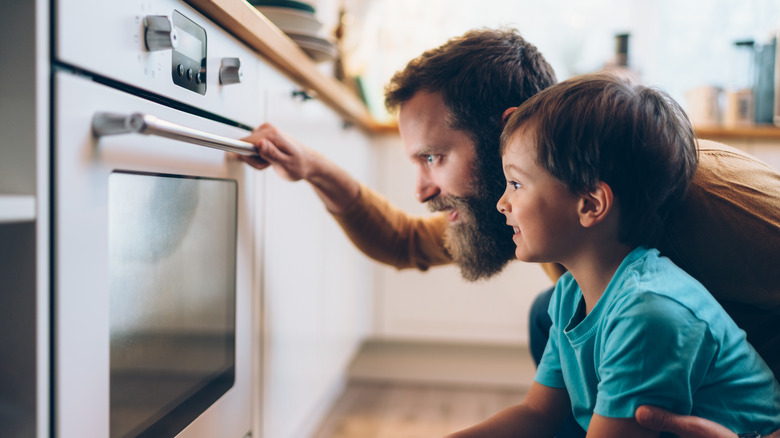 father and son looking into oven