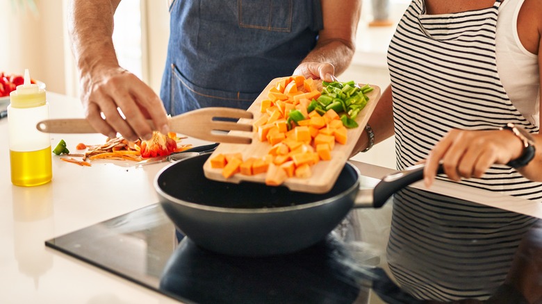 Couple putting carrots in pan