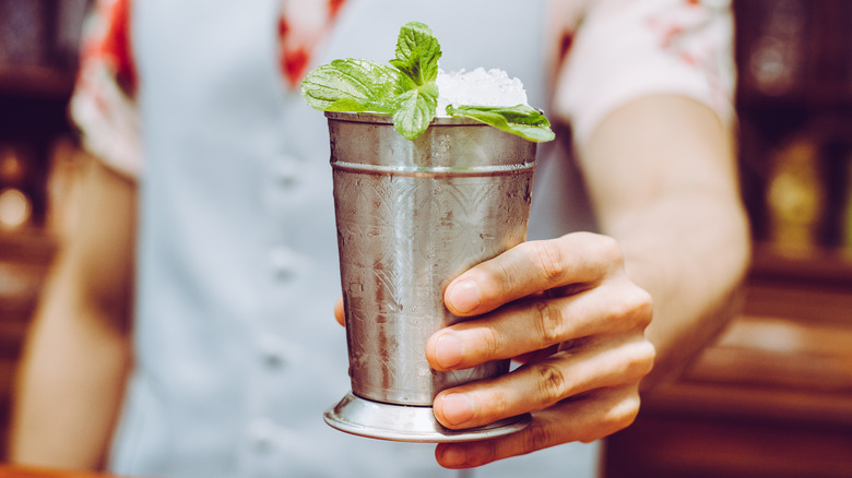 Bartender serving an icy mint julep cocktail in a silver cup