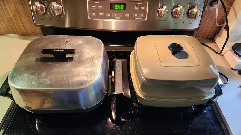 Two electric frying pans sit on a stove.
