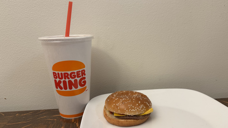 Cheeseburger on plate next to Burger King soft drink
