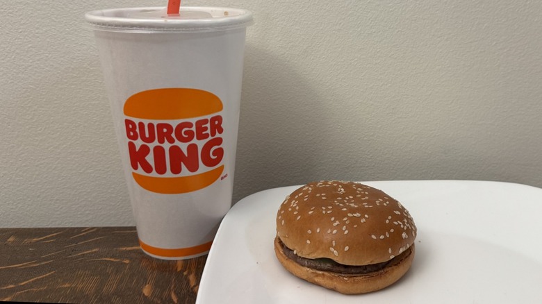 Hamburger on plate next to Burger King soft drink