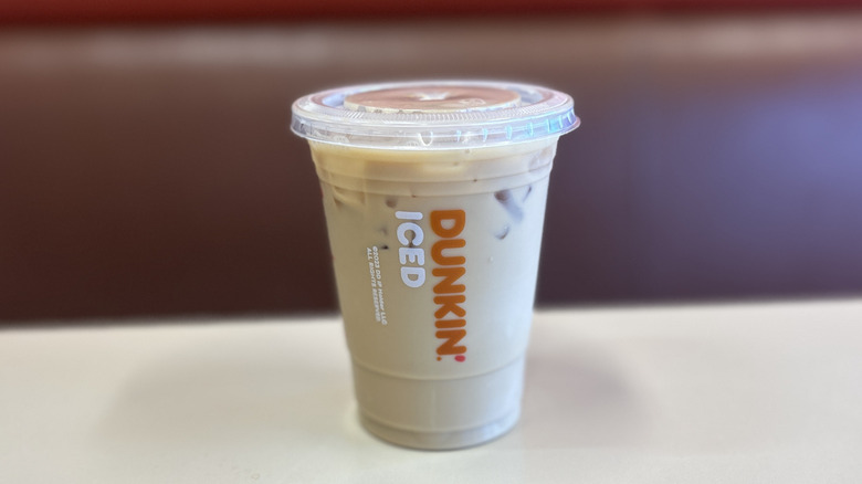 Raspberry iced coffee on a white table with the plastic lid on top