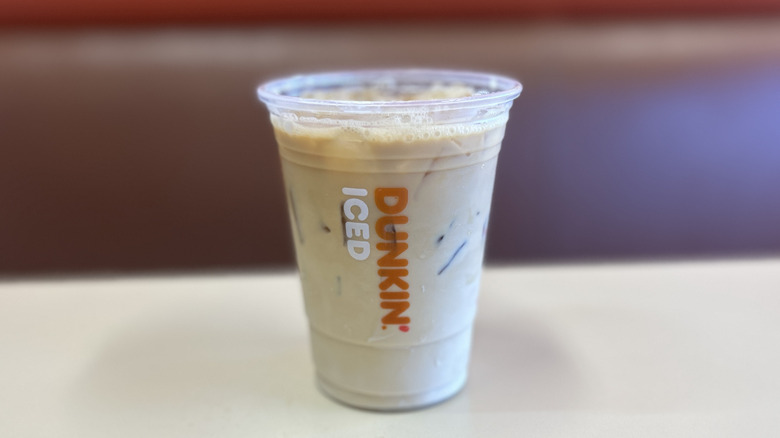 Coconut iced coffee on a white table with the plastic lid off