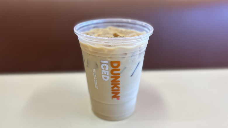 Butter pecan iced coffee on a white table with the plastic lid off