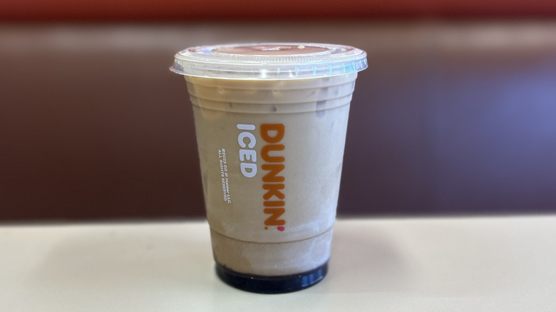 Mocha iced coffee on a white table with the plastic lid on top