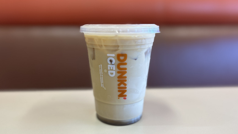 Brown sugar iced coffee on a white table with the plastic lid on top