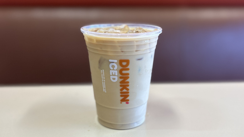 Hazelnut iced coffee on a white table with the plastic lid off