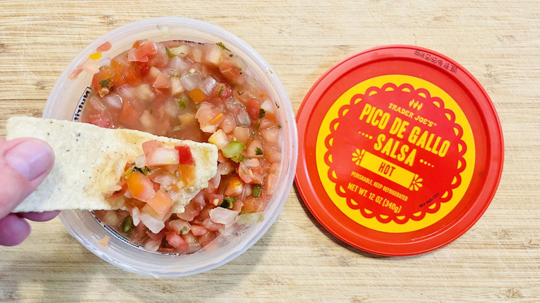 Hand dipping chip in Trader Joe's Hot Pico De Gallo Salsa
