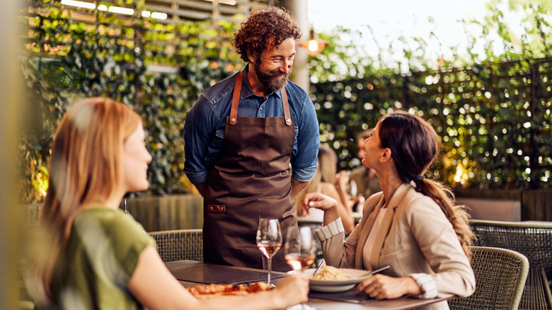 A waiter and a diner having a friendly interaction at a restaurant.