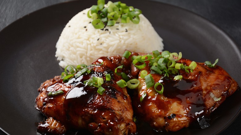 black plate with chicken adobo and white rice