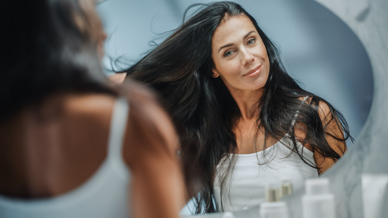 woman fixing her hair in mirror