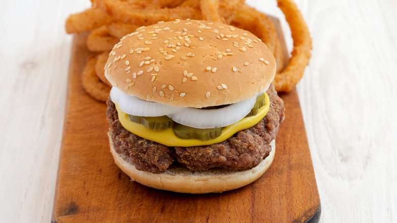 A slugburger on a wooden serving board with onion rings