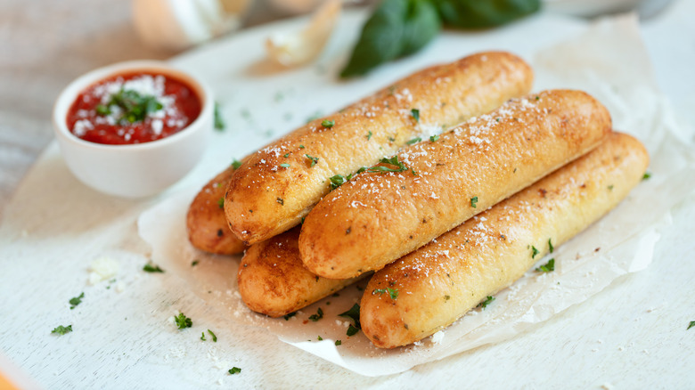 pile of breadsticks with marinara