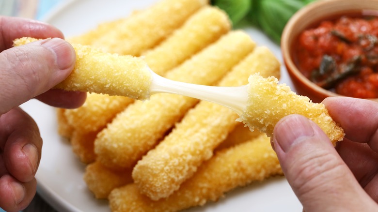 hands breaking mozzarella stick